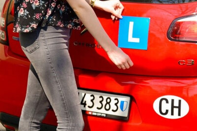 Eine Person bringt das L am Heck eines Autos