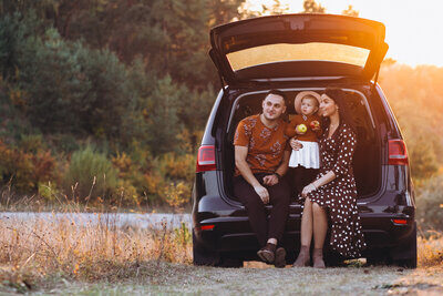 Familie mit kleiner Tocher im Kofferraum sitzend
