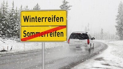 Auto auf der Strasse mit verschneitem Strassenrand.