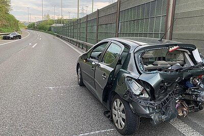 Nach der Kollision steht der stark beschädigte Peugeot in falscher Richtung auf der Autobahn. Im Hintergrund ist das unfallverursachende Fahrzeug, der Mercedes AMG zusehen. Bild: Kantonspolizei Zürich