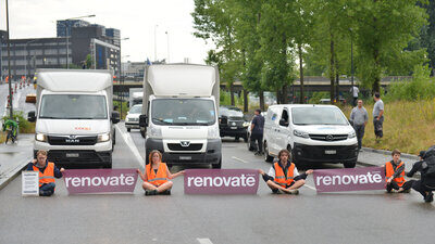 Klimakleber vor blockierten Autos am Boden sitzend
