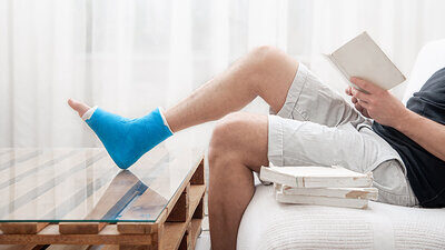 Mann mit gebrochenen Bein liest Buch