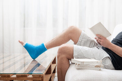 Mann mit gebrochenen Bein liest Buch