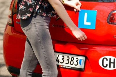 Eine Person bringt das L am Heck eines Autos