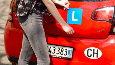 Eine Person bringt das L am Heck eines Autos