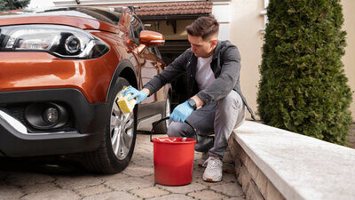 eine Person wäscht ihr Auto Zuhause