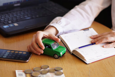 Person am Tisch mit Geld, Handy und Notizbuch.